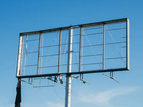 An empty billboard frame against a clear blue sky