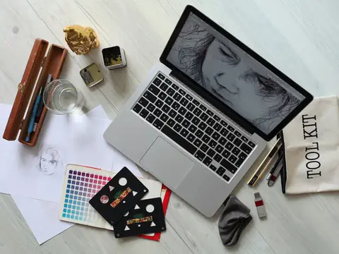A laptop, color swatches and sketches spread across a light desk