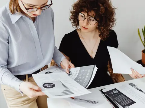 Two colleagues looking over a printed report at a bright desk