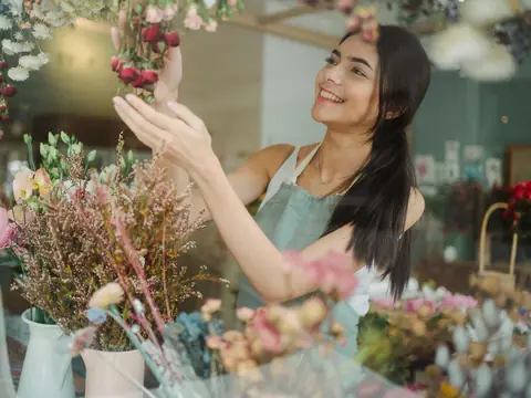 A florist arranging flowers in her bright shop