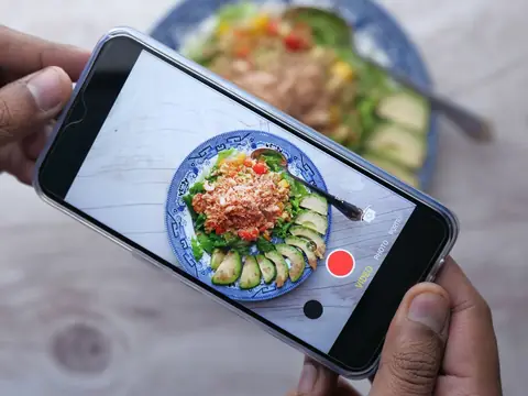 Filming a colorful salad with a smartphone at a table