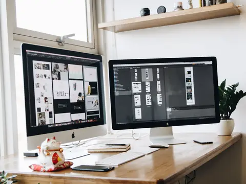Website layouts open on two large monitors in a bright studio