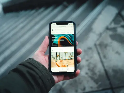 A hand holding a phone that shows a business website